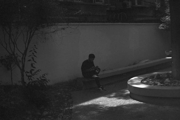 Ilford FP4 Plus 125 (FF)

• English Alt Text: A person sits on a bench in a shaded outdoor area, reading a book. The setting includes leafy trees, a curved concrete structure, and a circular planter filled with pebbles.
• 中文替代文本：一个人坐在阴凉的户外长椅上阅读书籍。环境中有茂密的树木、弯曲的混凝土结构和一个装满鹅卵石的圆形花坛。