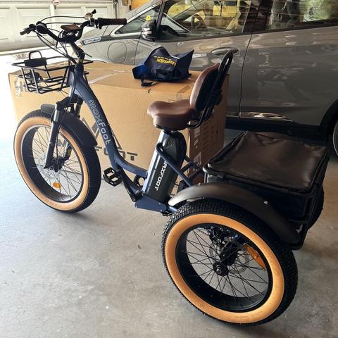 iPhone photo of my new blue electric trike with fat whitewall tires in our garage with its giant cardboard box and my little grey Chevy in the background