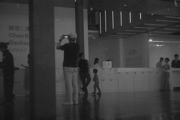 Ilford FP4 Plus 125 (FF)

English Alt Text:
Indoor scene at an exhibition or museum. People are walking, taking photos, and standing near a counter. Lockers numbered 29–34 are visible.

中文替代文字：
展览或博物馆内景。有人在拍照、走动或站在接待台附近。有编号为29到34的储物柜。