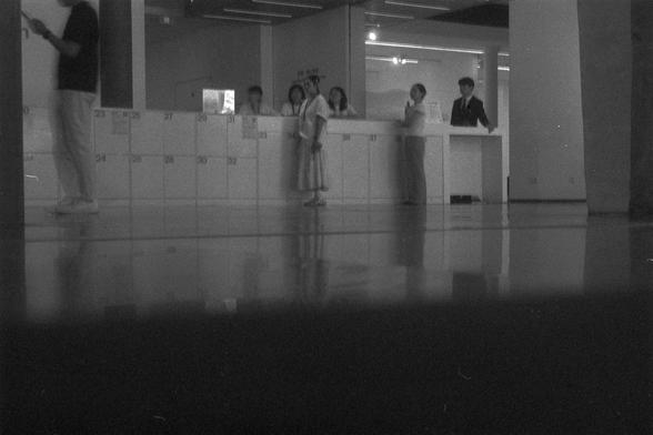 Ilford FP4 Plus 125 (FF)

English Alt Text:
A modern reception area with several people interacting. Numbered lockers (23–38) are visible in the background, and the highly reflective floor creates a mirror-like effect.

中文替代文字：
一个现代化接待区，几位人正在交流。背景中可见编号为23到38的储物柜，地板光滑如镜，反射出周围景象。