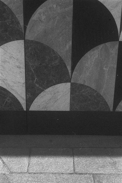 Ilford FP4 Plus 125 (FF)

• English alt text: A geometric pattern made of alternating dark and light semi-circles arranged in a grid on a wall or floor. A tiled surface appears at the bottom with a shadow cast across it.
• 中文替代文字：一个几何图案，由深浅相间的半圆组成，排列成网格状，可能是墙面或地板。图像底部是瓷砖地面，上面投下了一个阴影。