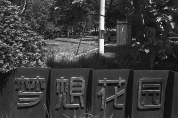 Ilford FP4 Plus 125 (FF)
• English Alt Text: A peaceful park scene with a sign in the foreground reading “Dream Garden” in Chinese characters, surrounded by trees, grass, and a pathway.
• 中文替代文字：一个宁静的公园场景，前景是一块写有“梦想花园”中文字样的标牌，周围有树木、草地和小路。