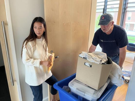 A student holding open a door while the Dean brings in items.