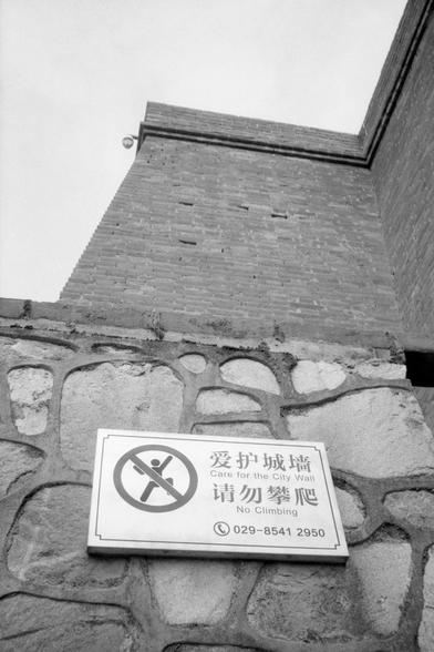 Kentmere Pan 200 (FF)

English Alt Text:
A stone wall with a mounted sign in both Chinese and English. Above the stone wall is a brick structure, likely part of a historic city wall. The sign reads “Care for the City Wall. No Climbing” and includes a red prohibition symbol of a person climbing. A phone number is listed for inquiries. The image emphasizes preservation and safety, discouraging physical interaction with the historic structure.

中文替代文字：
画面展示了一堵石墙，墙上挂有中英文提示牌。石墙上方是砖砌结构，可能是古城墙的一部分。提示牌…
