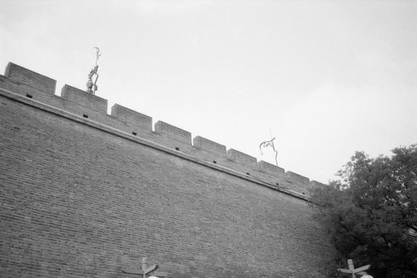 Kentmere Pan 200 (FF)

English Alt Text:
A black-and-white photo of a historic brick wall with a crenellated top, resembling a fortress or city wall. Two metal poles are mounted on the wall. The wall is weathered, suggesting age and historical significance. A tree is partially visible on the right, indicating the wall is outdoors. The sky is overcast, casting a muted tone over the scene. The image evokes a sense of timelessness and cultural heritage.

中文替代文字：
这是一张黑白照片，展示了一段具有历史感的砖墙，顶部呈锯齿状，类似城墙或…