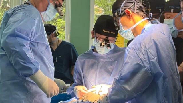 Doctors in surgical scrubs around a patient.