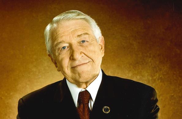 A man with white hair, wearing a suit.