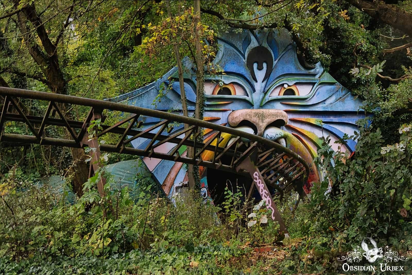 rollercoaster going into tunnel. Tunnel is shaped like a giant cat head, blue with rainbow cheeks