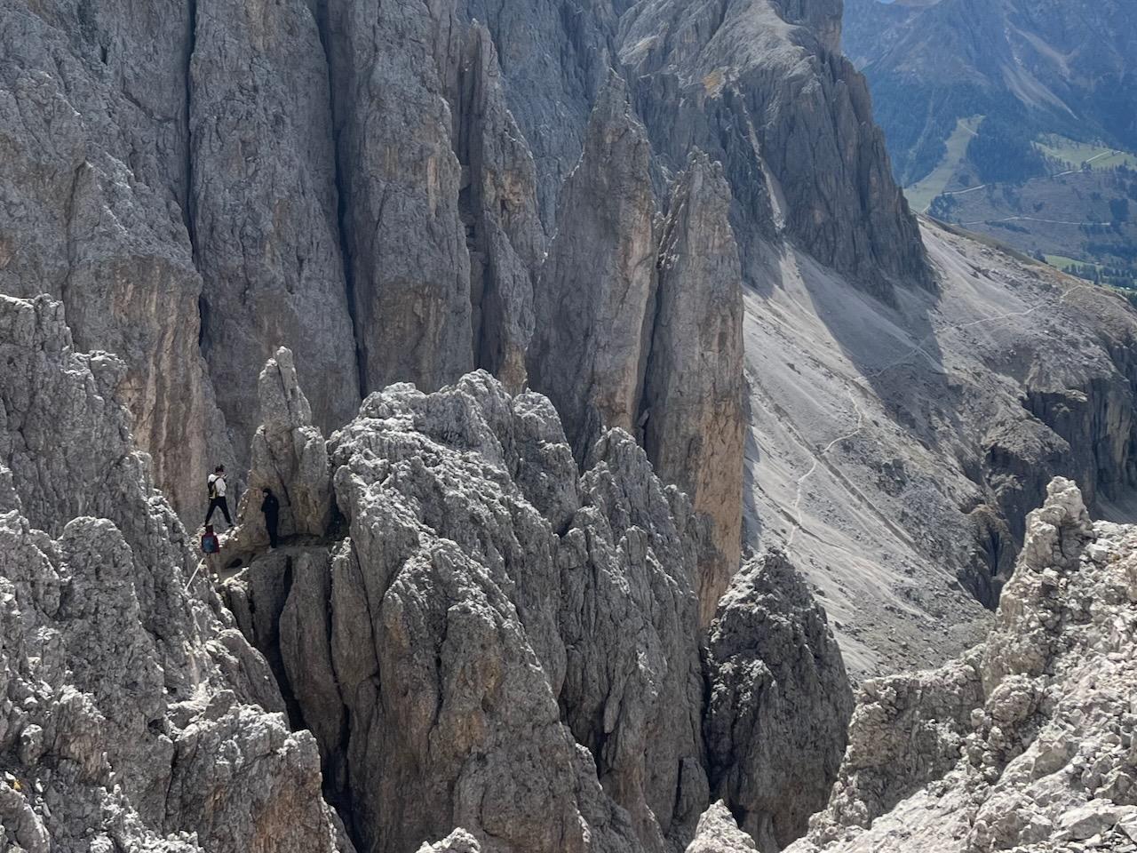 A person standing in a V-shaped opening of a rock ridge, surrounded by beautiful limestone/dolomite cliffs.