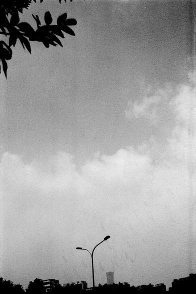 Lucky Lucky SHD 400 (FF)

English Alt Text:
A minimalist black-and-white city scene. A streetlight with two lamps stretches across the foreground. Behind it, rooftops of buildings peek into view. The sky dominates the image, filled with soft clouds and a gradient of light. In the upper left, tree branches and leaves form dark silhouettes, adding a natural touch to the urban setting. The composition feels calm and spacious.

中文替代文字：
这是一幅极简风格的黑白城市景象。前景中是一盏路灯，灯臂向两侧延伸。背景中可见几栋建筑的屋顶。天空占据画面大部分，云层柔和，光线…