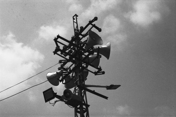 Lucky Lucky SHD 400 (FF)

English Alt Text:
A black-and-white image of a tall metal pole with multiple loudspeakers facing different directions, designed for wide-area sound coverage. A floodlight is mounted lower on the pole. The sky is partly cloudy. The setup suggests use for public announcements or emergency alerts. The monochrome tone gives the image a vintage or documentary feel.

中文替代文字：
黑白照片显示一个高大的金属杆，上面安装了多个朝不同方向的扩音器，用于广域广播。杆子下方还有一个泛光灯。天空部分多云。此结构可能用于公共广播或紧急警报。黑白色调为画面增添了复古或纪录片风格。
