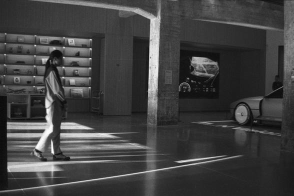 Ilford HP5 Plus 400 (FF)

English Alt Text:
A modern showroom with polished concrete floors and industrial-style pillars. A person walks across the space. On the left, shelves display books or merchandise, and a small cart is nearby. On the right, part of a sleek car is visible in front of a large digital screen showing futuristic vehicle graphics like a speedometer. The word “NIO” is printed on the floor, indicating this is an electric vehicle brand’s experience center.

中文替代文字：
一个现代展厅，地面为抛光混凝…