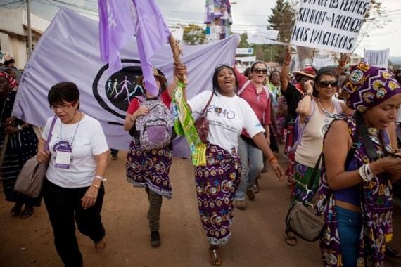 Photo of the march, with women wearing kente cloth and carrying banners.