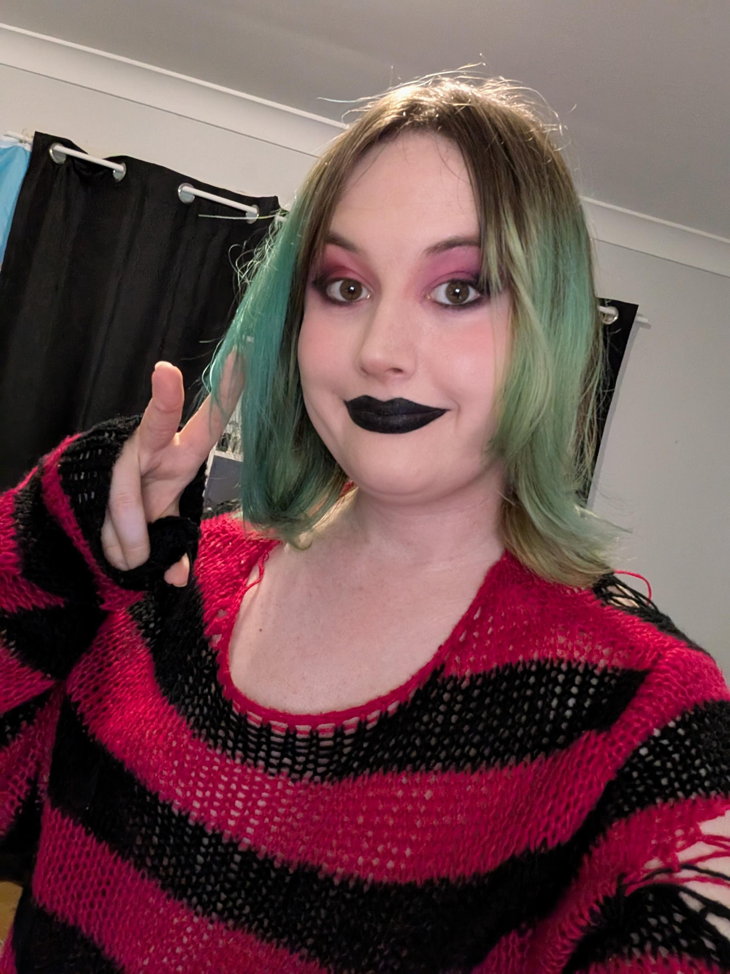 Revy wearing pink and black eyeshadow and black lipstick.
She's wearing a red & black fleece sweater