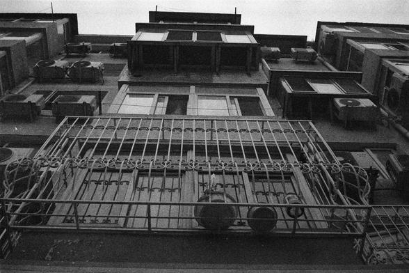 Shanghai GP3 400 PAN (FF)

English Alt Text: A dramatic black-and-white photo taken from a low angle, looking up at a tall residential building. The structure features multiple balconies with metal railings, windows with air conditioning units, and ornate ironwork. The perspective emphasizes the building’s height and repetitive architectural patterns. The grainy texture adds a vintage, film-like feel, highlighting the imposing presence of the urban architecture.

中文替代文字：
这是一张黑白照片，从低角度仰拍一栋高层住宅楼。…