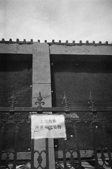 Shanghai GP3 400 PAN (FF)

English Alt Text: A black-and-white photo of a deteriorating building facade. In the foreground, a metal fence has a crumpled paper sign taped to it. The sign reads in Chinese: “Danger above. Beware of falling objects.” The building wall behind the fence shows cracks and rough textures, suggesting structural decay. The image conveys a sense of caution and urban neglect.

中文替代文本： 这是一张黑白照片，展示了一栋破旧建筑的外墙。前景中是一道金属围栏，围栏上贴着一张皱巴巴的纸质警示牌。牌子上写着：“上方危险 注意高空坠物。”围栏后面的墙面有裂缝和粗糙的质感，显示出…
