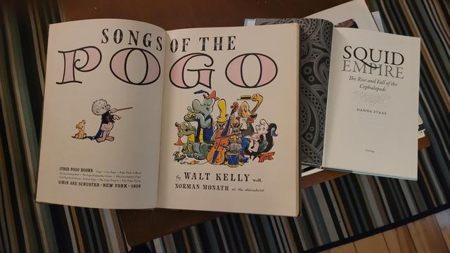 Books open to their inner cover pages, spread out on a coffee table. Books open to their inner cover pages, spread out on a coffee table.