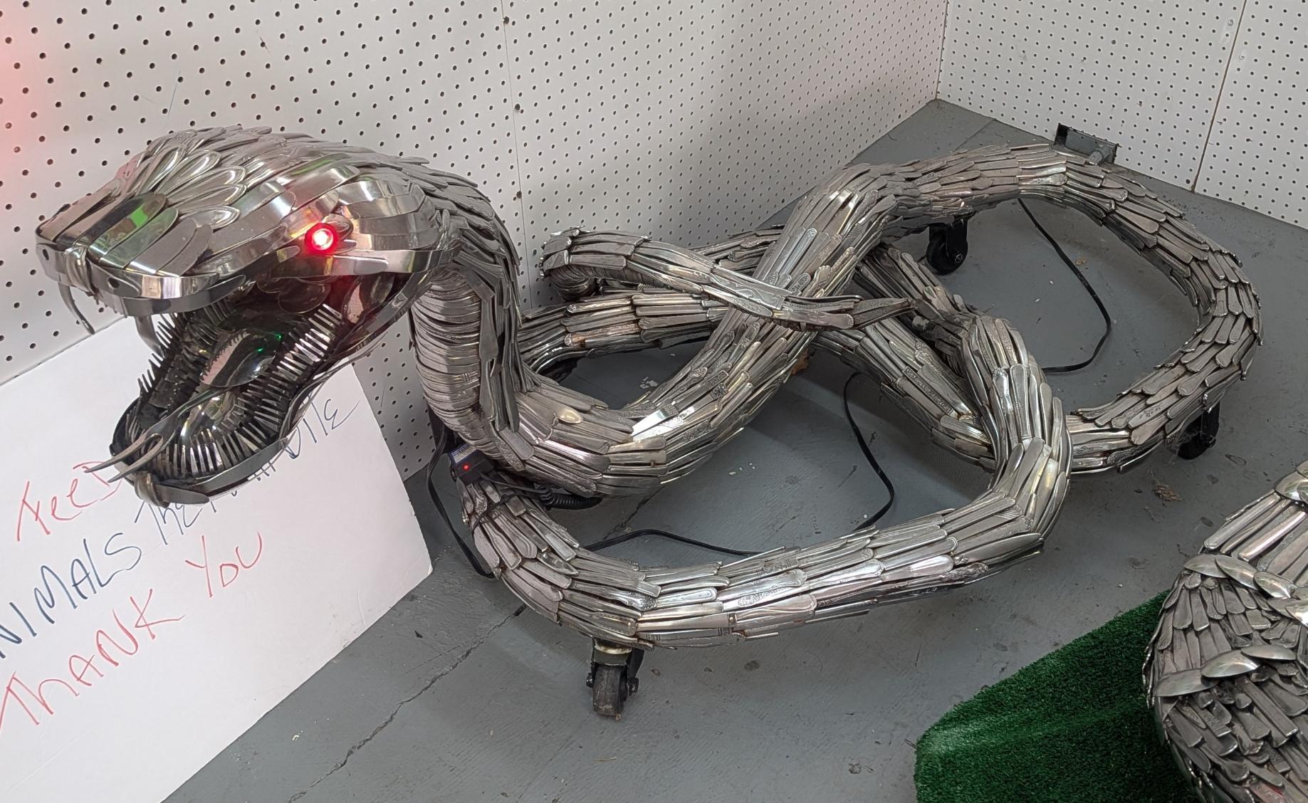A sculpture made of discarded silverware on the shape of a coiling snake.