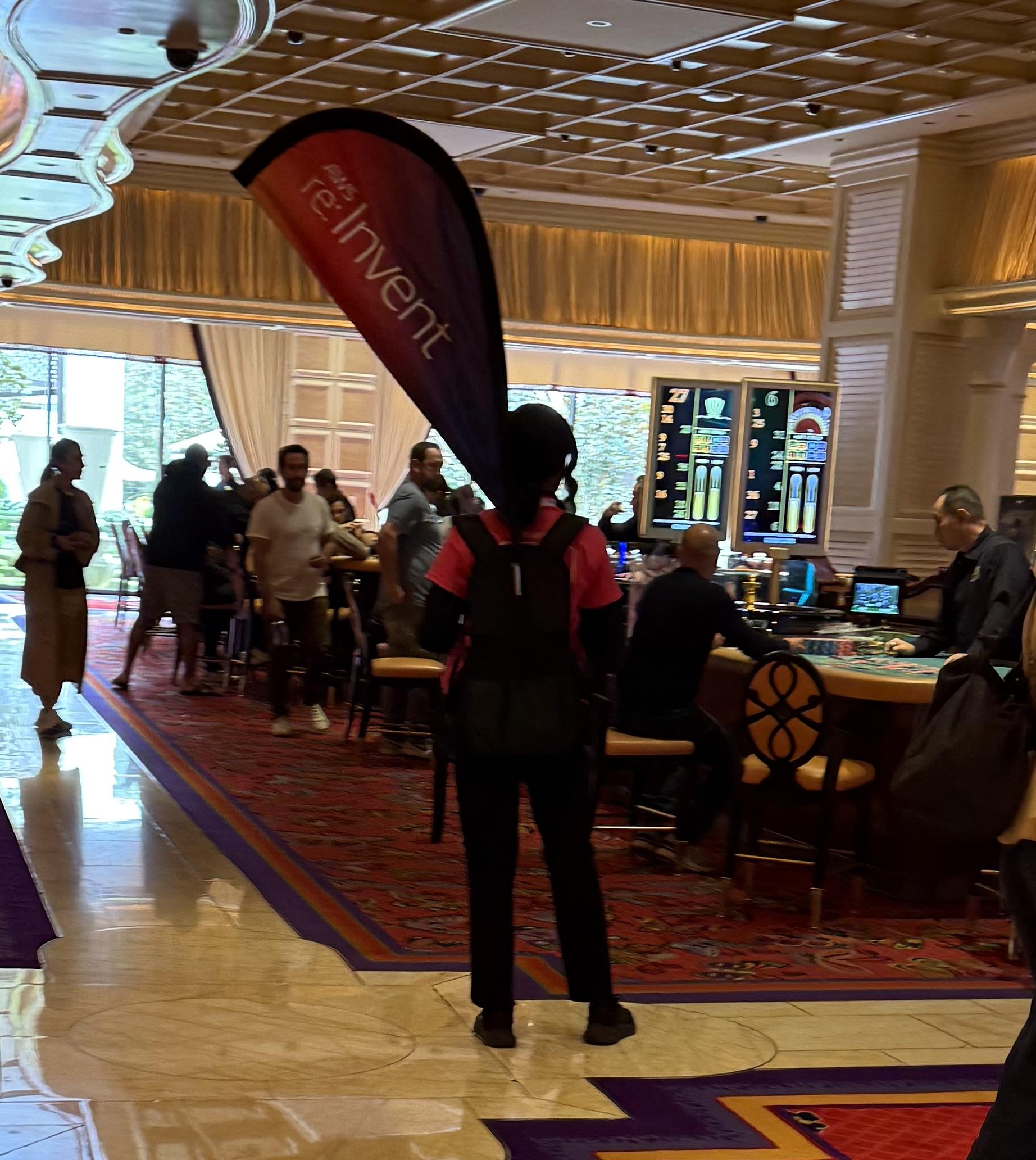 A person standing with a large banner with the convention’s name at an intersection of pathways in a casino.