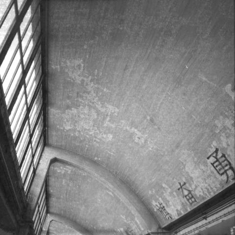 Ilford HP5 Plus 400 (6x6)

English Alt Text: A black and white image captures the interior of a large building with an arched ceiling and tall windows on the left. The ceiling appears weathered, with visible streaks and patches. On the right wall near the ceiling, large Chinese characters are painted, suggesting cultural or historical significance. The architecture hints at a public space, possibly a train station or hall in a Chinese-speaking region.

中文替代文字： 这是一张黑白照片，展示一座大型建筑的内部，拱形天花板高耸，左侧排列着…