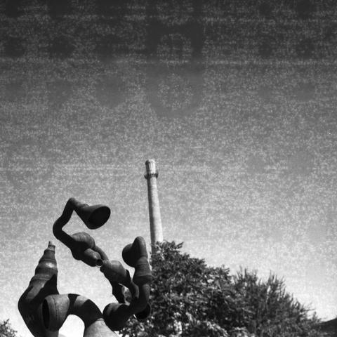 Ilford HP5 Plus 400 (6x6)

English Alt Text: A black and white photograph features a metal abstract sculpture in the foreground, composed of twisted tubular forms resembling horns or funnels. Behind it stands a tall industrial chimney, rising vertically into a grainy sky. Trees surround the sculpture, adding contrast between nature, art, and industry. The sculpture’s flowing shapes juxtapose the rigid geometry of the chimney, creating a visual tension between creativity and functionality.

中文替代…