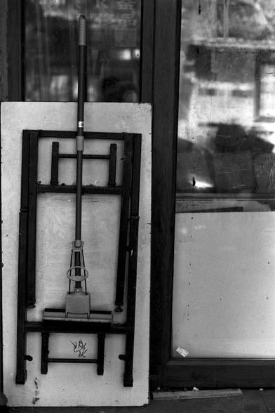 Ilford Pan 100 (FF)

English Alt Text: A black-and-white photo of a mop leaning against a folded table in front of a glass door. The mop has a long handle and a sponge head. The table, made of metal and wood, is folded flat with visible legs. A small graffiti-like symbol is drawn near the bottom center of the table. The glass behind is dirty and reflects vague shapes and light, suggesting an outdoor setting. The composition highlights everyday objects with artistic framing and contrast.

中文替代文字…