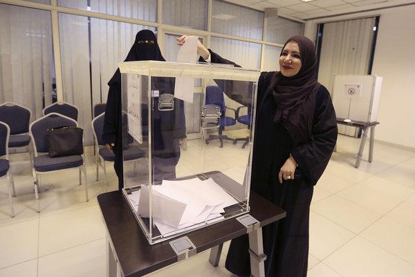 A woman in a hijab posting her vote into the ballot box.