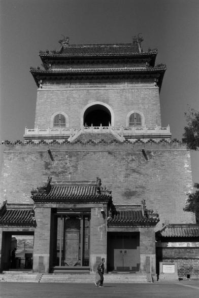 Ilford Pan 100 (FF)

English Alt Text: Black-and-white image of a grand traditional Chinese tower, possibly a bell or drum tower. The structure features ornate tiled roofs with upturned eaves and decorative carvings. A central arched opening is visible on the upper level. The building is made of brick and stone, with a wide staircase leading up. A person walks in the foreground, emphasizing the tower’s scale. The scene captures cultural heritage and architectural elegance.

中文替代文字：
这是一张黑白照片，展示了…