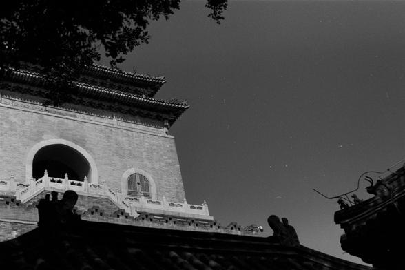 Ilford Pan 100 (FF)

English Alt Text: Black-and-white photo of a majestic Chinese building with a tiered roof and intricate details. The structure has arched windows, brick walls, and a balcony with balustrades. The roof features upturned eaves and carved decorations. In the foreground, a silhouetted roofline includes animal-like sculptures, possibly dragons or deer. Tree branches frame the top of the image. The scene highlights classical Chinese architecture and symbolic ornamentation.

中文替代文…