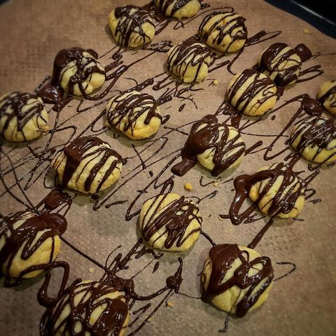 Helle Kekse auf einem Backblech. Sie sind mit dicken Striemen aus Sckokolade garniert.