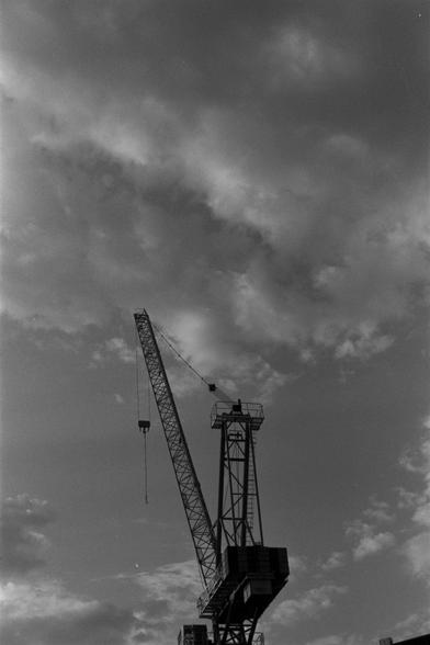 Ilford Pan 100 (FF)

English Alt Text:
A tall construction crane stands against a cloudy sky in a black-and-white photograph. The crane’s long boom angles upward, with a hook hanging from its tip. The structural tower supporting the boom is made of metal latticework. The sky is filled with textured clouds, creating a dramatic contrast with the industrial silhouette. The image emphasizes the height and geometry of the crane, evoking a sense of scale and strength.
中文替代文本：  
这是一张黑白照片，画面中是一台高大的建筑起重…