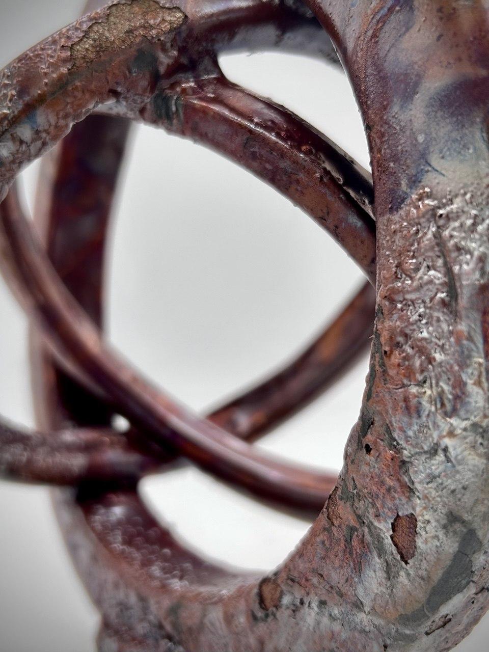 A closeup of the industrial glazing on a copper red and purple raku pottery sculpture