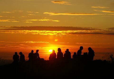 People silhouetted against a sunset or sunrise