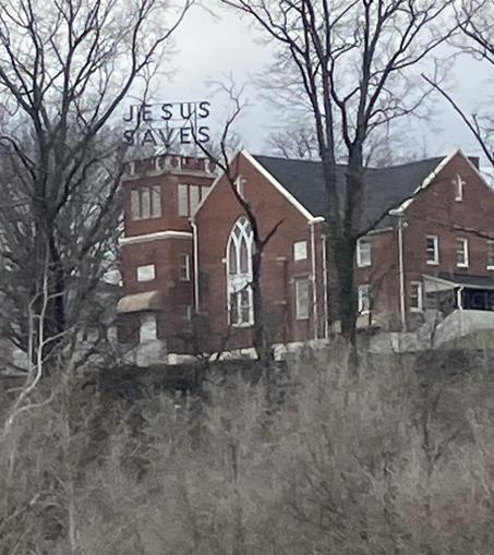 A red brick church building featuring a prominent sign that reads "JESUS SAVES." It sits on the hill across the Roanoke River from Vic Thomas Park, at the top of my run.