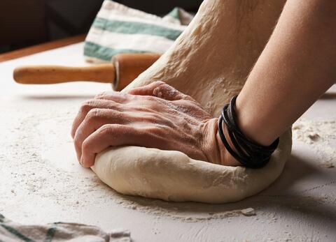 A person kneading dough. Perhaps pizza dough?