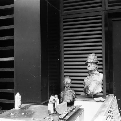 Lucky SHD 400 (6x6)

English Alt Text:
A monochrome photo of an urban workspace featuring two sculpted busts placed near a wall with horizontal slats. One bust wears a hat and is more defined; the other is smaller and abstract. In front of them lie spray paint cans, a brick, and scattered tools. The gritty textures and industrial backdrop suggest a creative or artistic environment, blending sculpture with street art elements.
中文替代文字：
这是一张黑白照片，展示一个城市工作空间。两尊雕塑胸像摆放在带有横向通风板的墙边，一尊戴帽子，轮廓清晰，另一尊较小，形态抽象…