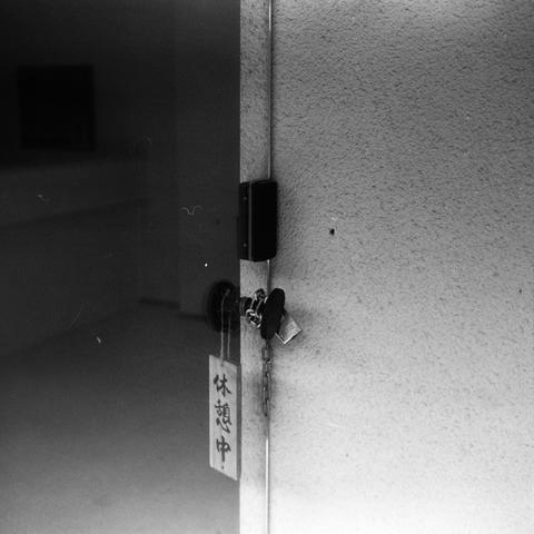 Lucky SHD 400 (6x6)

English Alt Text:
A close-up black-and-white image of a slightly open door with a chain lock and a key inserted. Attached to the keychain is a rectangular sign with Japanese text reading “休憩中,” meaning “On break.” The interior behind the door is dimly lit, suggesting a pause in activity. The textures of the metal lock, door surface, and shadows evoke a sense of stillness and temporary closure.
中文替代文字：
这是一张黑白特写照片，显示一扇微微打开的门，门上有链条锁，钥匙插在锁孔中。钥匙链上挂着一个矩形牌子，上面写着日文“休憩中”，意思是“休息中”。门后…