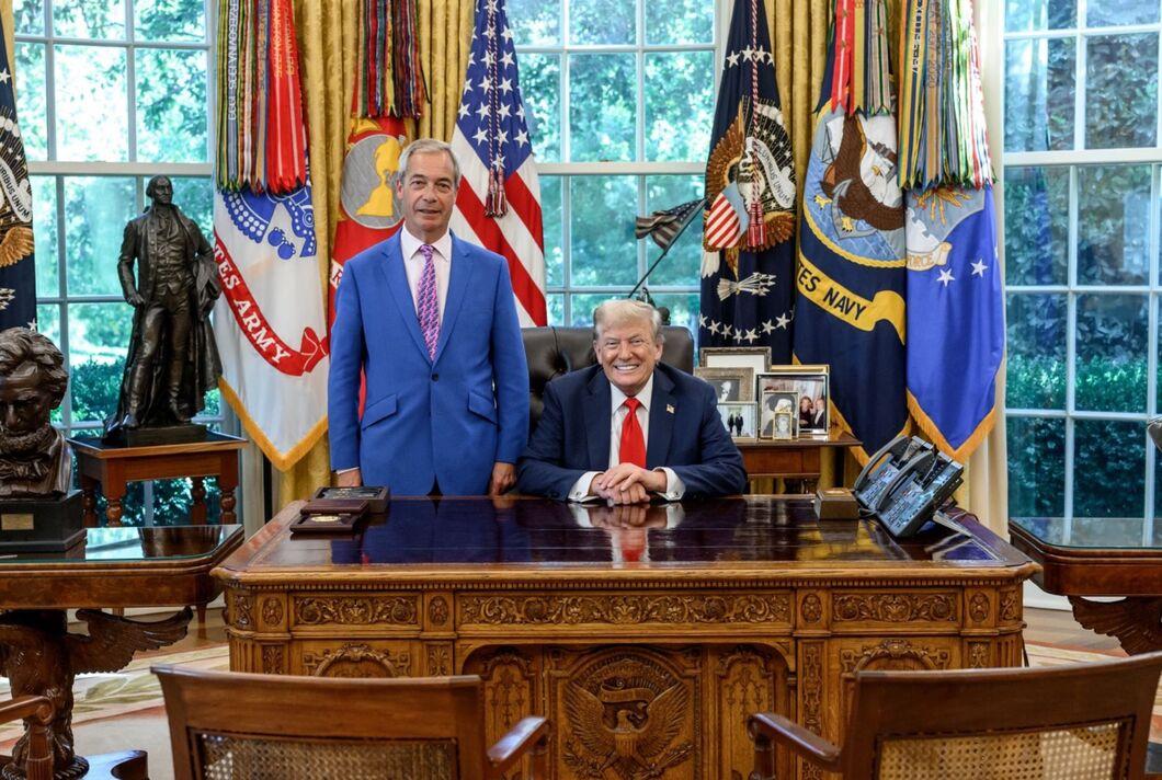 Farage standing smugly next to Trump, who's grinning and sitting at his desk in the oval office. Farage's suit is bright blue and he's wearing a pink tie, for reasons unfathomable.