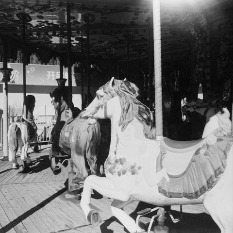 Lucky SHD 400 (6x6)

English Alt Text: A black-and-white photo of a traditional carousel featuring elaborately decorated horse figures with ornate saddles and bridles. The carousel sits on a wooden platform. The canopy above is adorned with decorative patterns. Bright sunlight highlights parts of the scene, casting dramatic shadows. In the background, signage with Chinese characters suggests the location is in a Chinese-speaking region. The image evokes nostalgia and whimsy, capturing the charm…