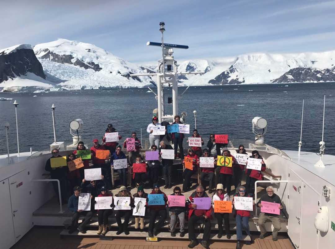 A photo of the Antarctic protest, with the crew of a scientific vessel holding up signs.