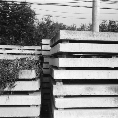 Lucky SHD 400 (6x6)

English Alt Text: A black and white photo of large rectangular concrete slabs stacked outdoors in neat piles. Each slab is separated by cylindrical spacers. One stack has dried plant debris on top. Trees and utility wires are visible in the background. The image emphasizes texture and contrast between industrial materials and natural elements. No people or vehicles are present.

中文替代文本：
这是一张黑白照片，展示户外整齐堆放的大型矩形混凝土板。每块板之间用圆柱形垫片分隔。一堆板上覆盖着干枯的植物残骸。背景中可见树木和电线。画面突出了工业材料与自然元素之间的质感和对…