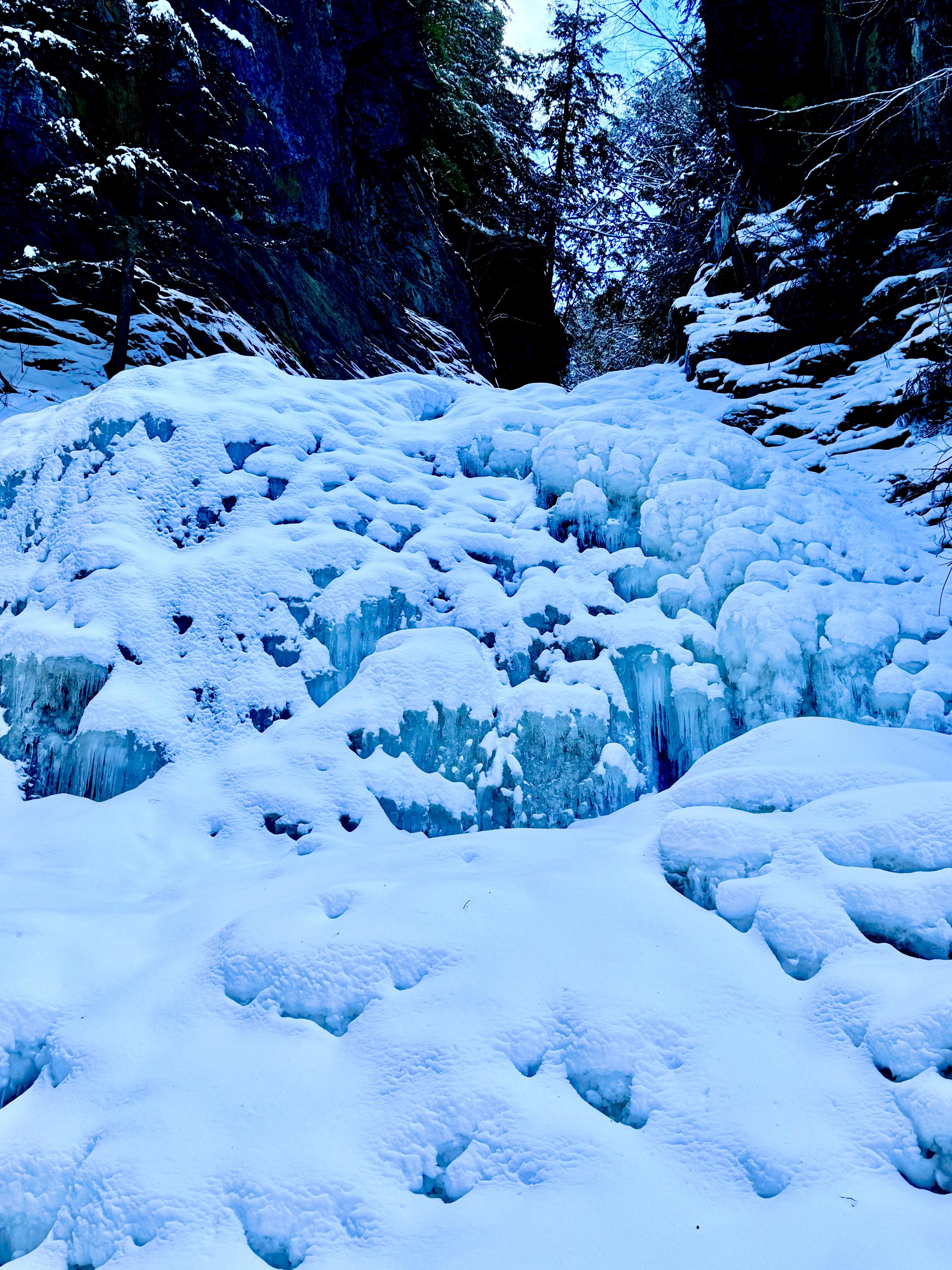 Photo taken from base of waterfalls looking up. Frozen snow-covered features of what used to be cascading water features. Forested area seen at top of falls.

Note: Although the exterior of the falls was frozen solid, there was still water flowing beneath the ice.

Moss Glen Falls. Approximately 125 feet tall.