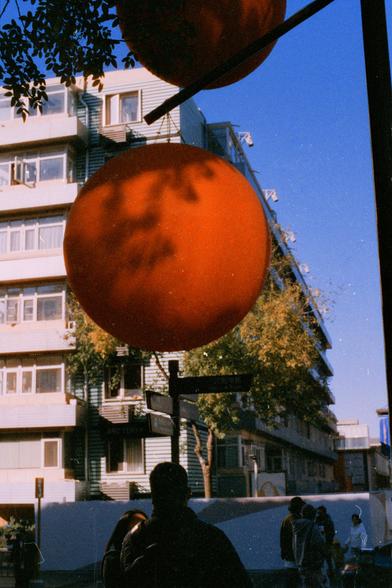 Harman Phoenix 200 II (FF)

English Alt Text
A large red lantern hangs in the foreground, its surface patterned with shadows from nearby tree branches. Behind it is a modern multi‑story building with horizontal lines and many windows. Several people walk along the street below, and signs with Chinese characters are visible. Warm late‑afternoon sunlight casts long shadows, creating a contrast between the traditional lantern and the contemporary urban setting.
Chinese Alt Text
画面前景是一盏大型红色灯笼，上面有树枝…