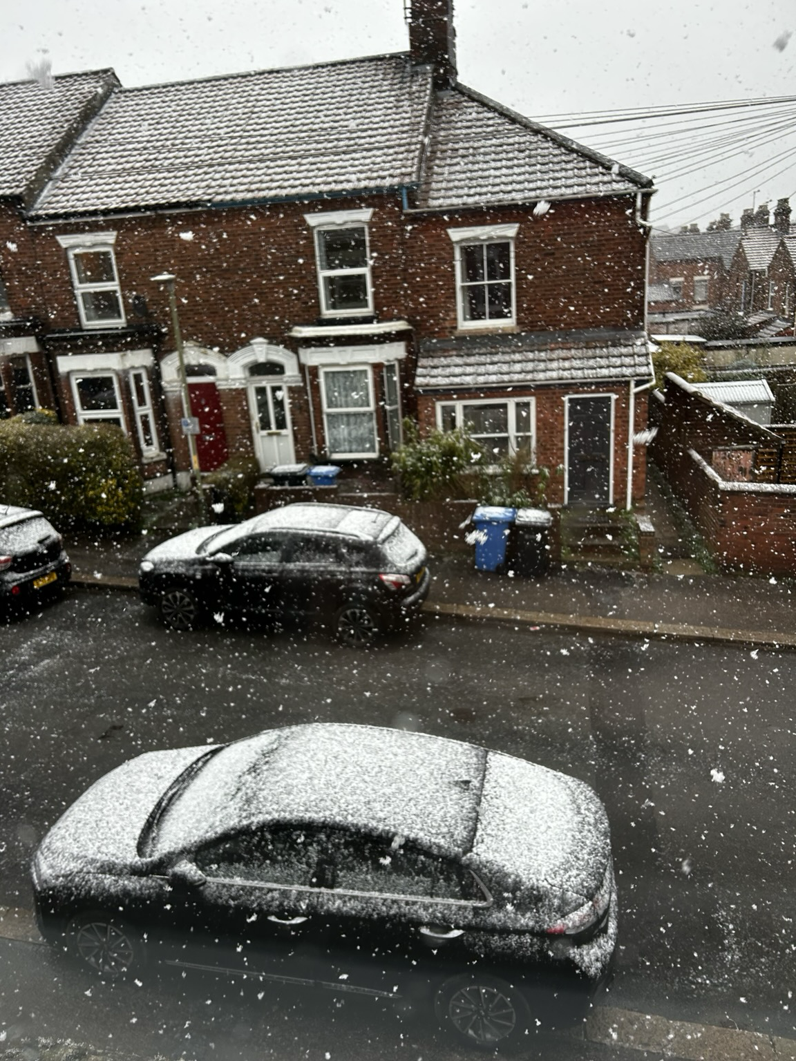 View of Victorian terrace street with thick snow flakes falling and settling on the cars