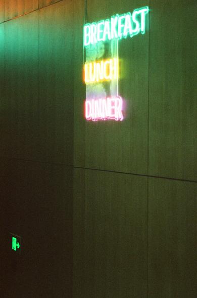 CineStill 800T (FF)

English Alt Text
A dark wall illuminated by a vertical neon sign listing three words: “BREAKFAST” in green, “LUNCH” in yellow, and “DINNER” in pink. The colored lights cast a soft glow on the wall. A small green emergency exit sign appears in the lower left corner.
Chinese Alt Text
一面黑暗的墙上挂着竖直的霓虹灯牌，上面写着三行字：“BREAKFAST”是绿色，“LUNCH”是黄色，“DINNER”是粉色。霓虹灯在墙面投射出柔和的彩色光。左下角有一个绿色的紧急出口标志。