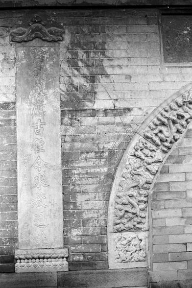 Rollei RPX 400 (FF)

English alt text
A black‑and‑white photograph of an ancient Chinese architectural detail. A vertical stone tablet with carved Chinese characters is set into a brick wall. Above it is an ornate decorative element resembling clouds. To the right, a semi‑circular arch is richly carved with dragons and swirling cloud motifs, suggesting a historical or temple setting.
中文替代文字
一张黑白照片，呈现中国古建筑细节。砖墙中嵌着一块刻有汉字的竖立石碑，上方有云纹装饰。右侧的半圆形拱门雕刻着龙与云纹，体现出历史或庙宇建筑的特色。