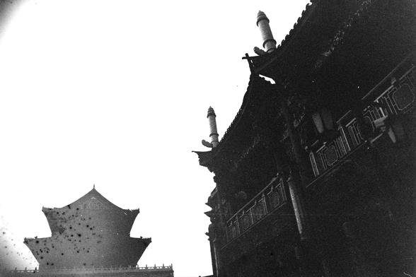 ERA 100 (FF)

Image 2 – English Alt Text
A black‑and‑white photograph showing two traditional East Asian buildings with upturned eaves. The building on the right is closer, revealing intricate roof decorations and railings. The building on the left appears farther away and is silhouetted against a bright sky. The strong contrast emphasizes the layered roofs and elegant architectural lines.
Image 2 – 中文替代文字
一张黑白照片，画面中有两座带飞檐的传统东亚建筑。右侧建筑较近，可看到精细的屋顶装饰和栏杆。左侧建筑较远，在明亮的天空前呈现剪影效果。强烈的明暗对比突出屋檐的层次与优美的线条。