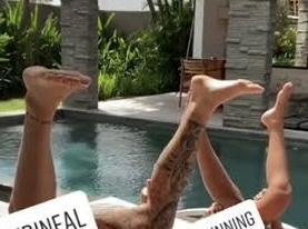 A heavily cropped photo of a man and woman that are perineum sunning. The photo is taken outdoors on a sunny day. Both people have their legs spread apart and pointed upwards toward the sub, exposing their perineum. I heavily cropped the photo so that all you see is from their knees to their feet.