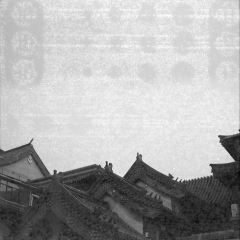 Ilford HP5 Plus 400 (6x6)

English alt text:
A black‑and‑white image showing a dense cluster of traditional East Asian rooftops. The roofs have ornate, curved eaves and decorative ridge details. The lower half of the image is filled with overlapping rooflines, while the upper half shows an empty sky with slight graininess, suggesting an older photograph.
中文替代文字：
一张黑白照片，呈现密集的东亚传统屋顶。屋檐弯曲精致，屋脊带有装饰细节。画面下半部被层叠的屋顶占据，上半部是略带颗粒感的天空，呈现出老照片的质感。
