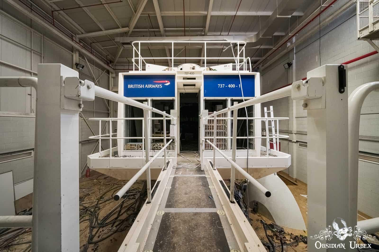 An abandoned British Airways 737-400 flight simulator facility. A walkway leads to the simulator